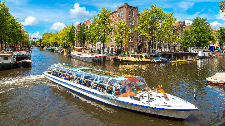 Tour boat cruising along Amsterdam canal