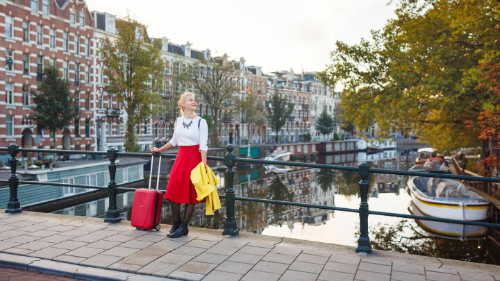 Female tourist with a suitcase leaning against canal railings