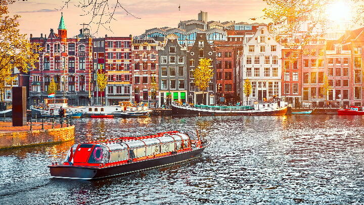 Canal boat passing by iconic Amsterdam canal houses