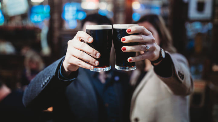 Couple toasting with pint glasses of Guinness.