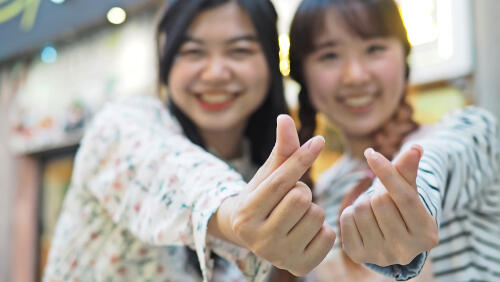 Two girls make K-pop mini hearts