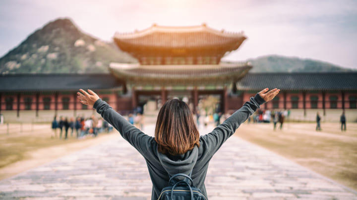 Woman raising her arms in celebration as she arrives at Gyeongbokgung Palace in Seoul.