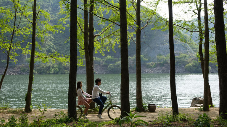 Two people cycle along a lake in Seoul