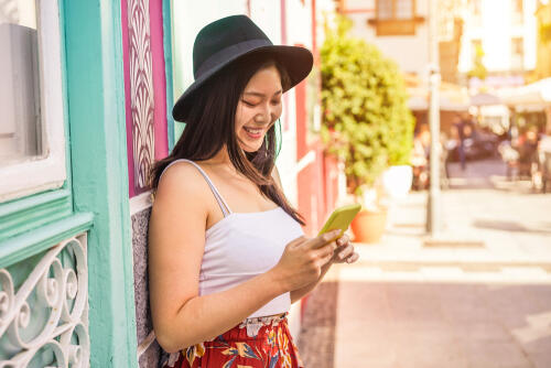 A young asian woman looking at her phone and smiling