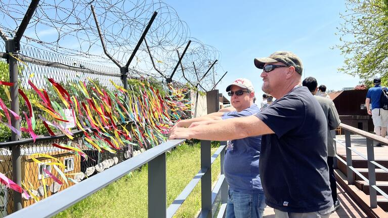 Men looking at the ribbons and barbed wire fence at the Demilitarized Zone in Korea