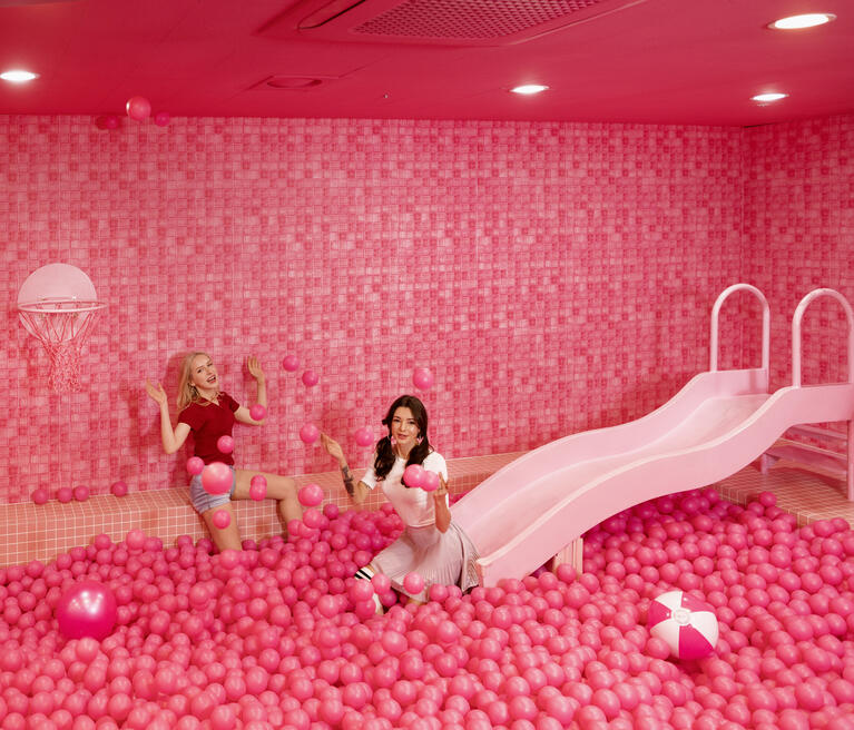 Two women play in a pink ball pit at Colorpool Museum, Seoul