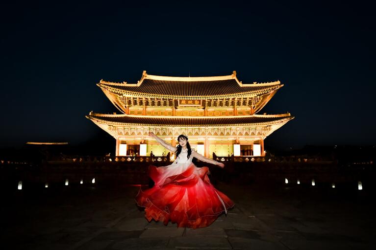 Seoul's palace at night with a woman in traditional costume