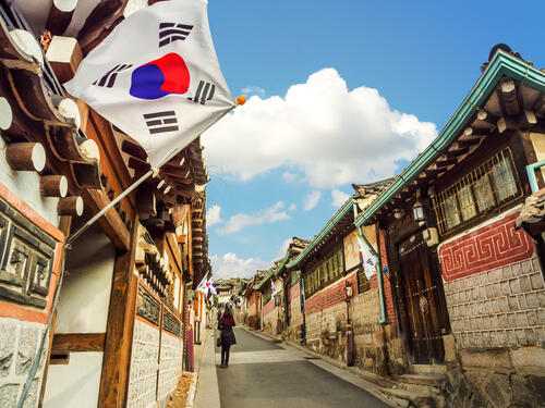 A narrow street in a traditional Korean village, with a Korean flag