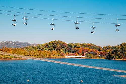 Cable car in Seoul Land travels over a lake and autumn colors