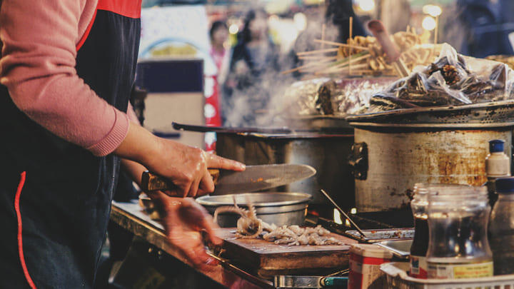 Street food hawker cooking food in a Seoul night market.