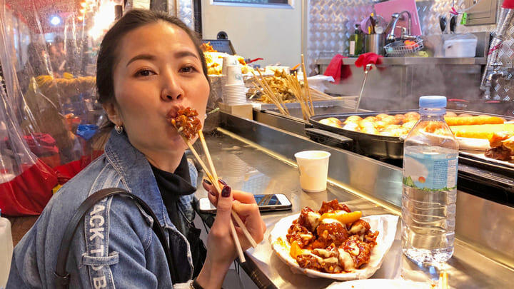 Woman dining out at a traditional Korean street food market.