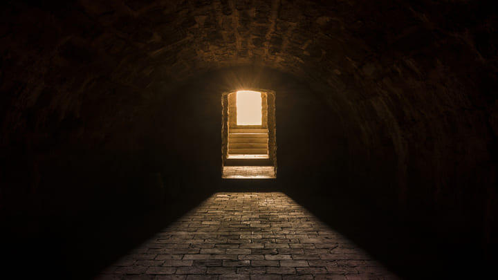 A spooky, dimly lit street with a backlit doorway at the end.