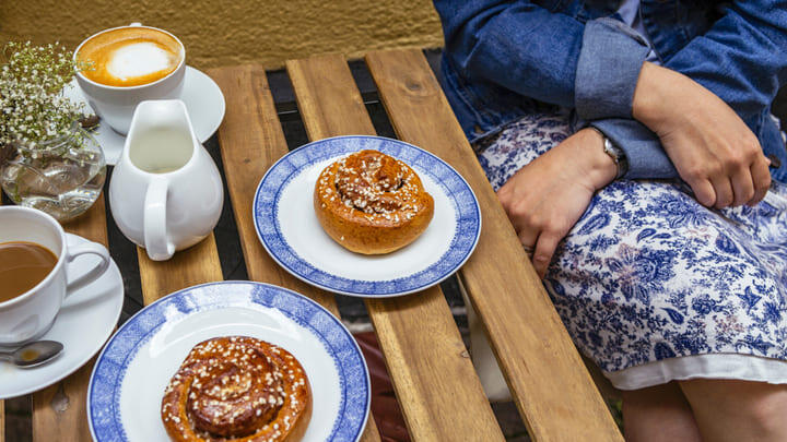 Woman sitting at a table with coffee and cinnamon buns
