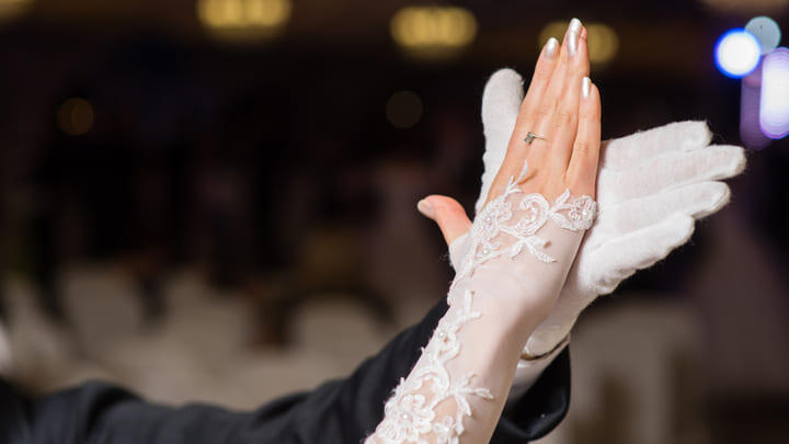 Close-up of waltz partners joining hands.