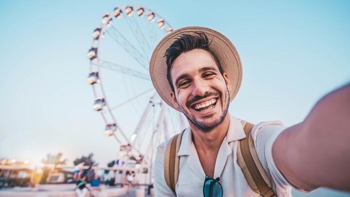 Tourist taking a selfie in front of the London Eye.