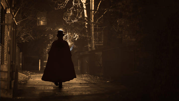 Cloaked figure walking along a dark alleyway.
