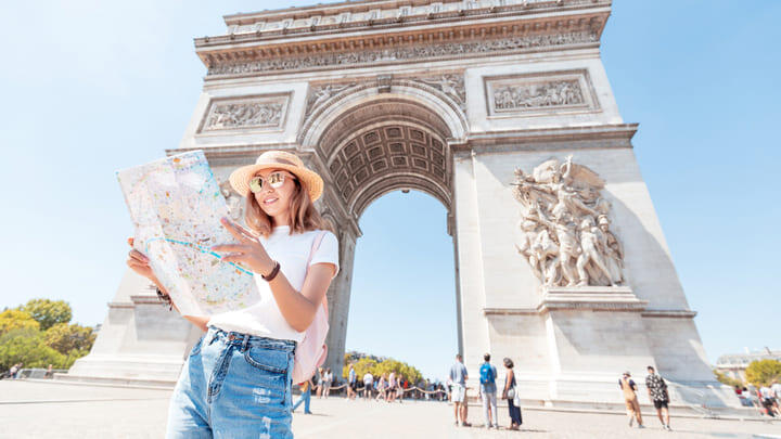 Woman consulting a map by the Arc de Triomphe in Paris.