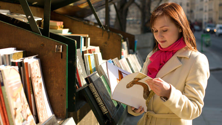 Woman look at books at one of Paris's bouquinistes stalls by the Seine.