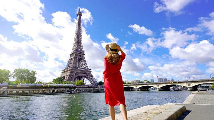 Woman looking at the Eiffel Tower across the Seine.