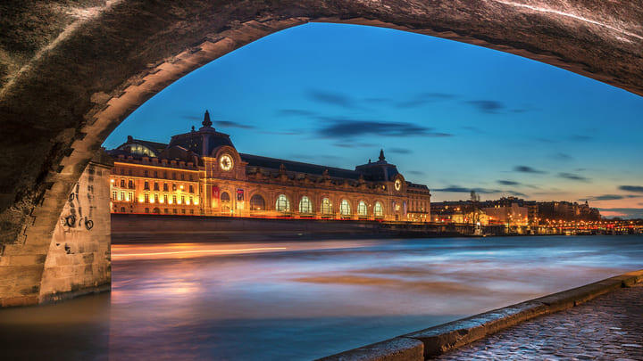 View of the Musée d'Orsay from beneath the arches of a Seine bridge n Paris.