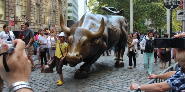 Wall-Street-Walking-Tour-1-600x300.jpg tourist posing with the Charging Bull statue on Wall Street Walking Tour