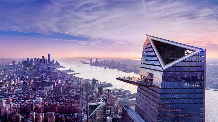 Purple tinged aerial view of NYC showing unique shape and protruding sky deck of Edge