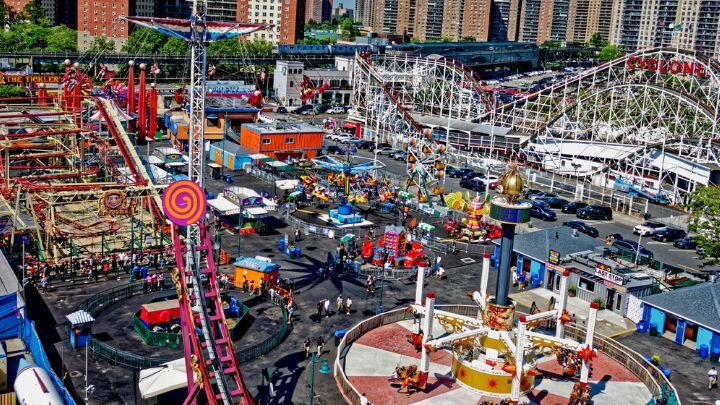 Brightly coloured rides at Luna Park Coney Island, including white wooden coaster, the Cyclone