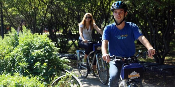 A man and a woman riding bikes through greenery.