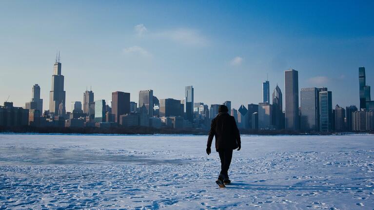 A man walks across snowy ground in Chicago