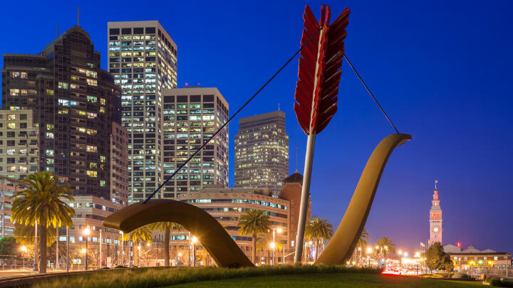 Cupid's Span statue in front of illuminatedSan Francisco skyline