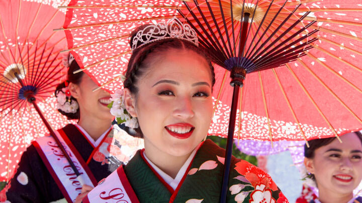 Smiling women in kimonos holding paper parasols for Northern California Cherry Blossom Festival