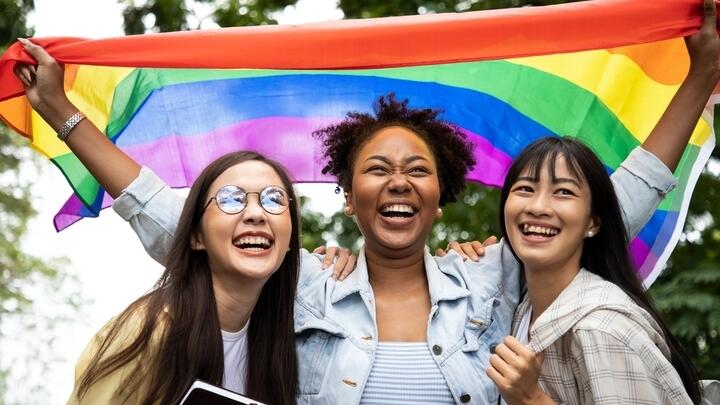 Young women celebrating Pride with a rainbow flag