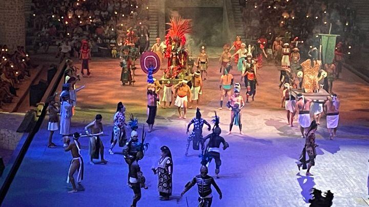 Blue lit overhead shot of multiple performers in traditional dress at arena show Xcaret