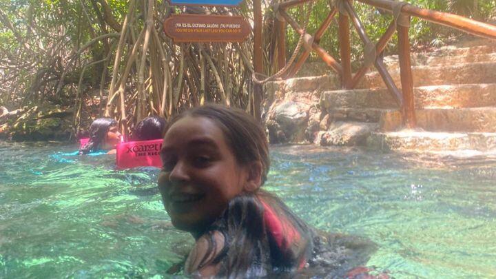 Smiling teen turns to camera during river swim in turquoise water, Xcaret park