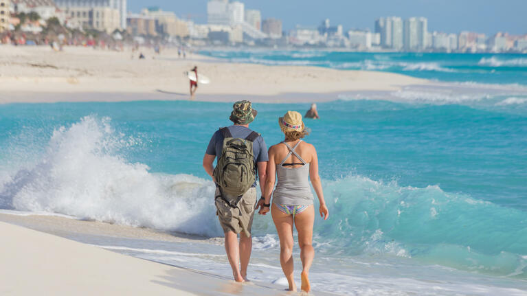 A couple stroll along the shoreline of Playa Delfines in Cancun