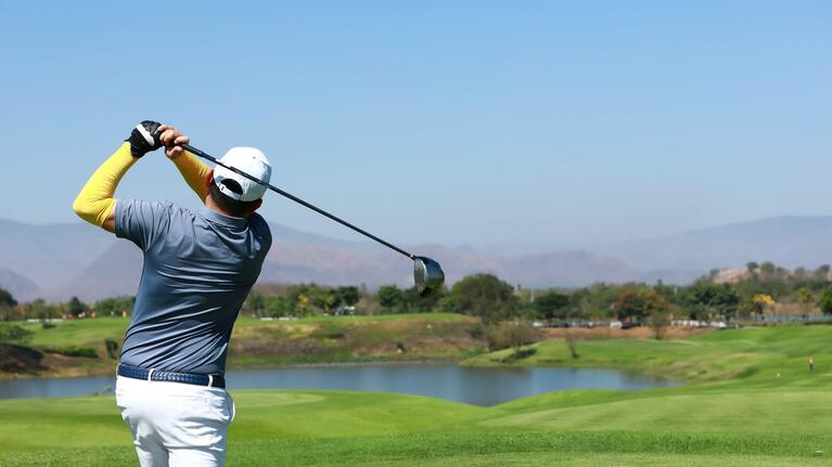 A golfer swings a club on the course
