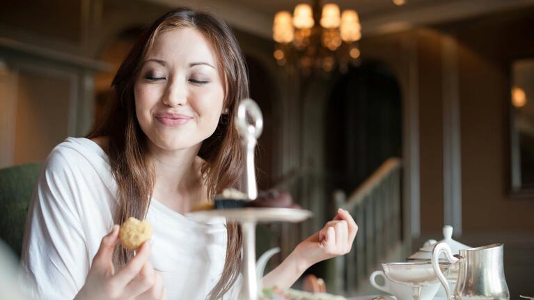 A young woman samples the cakes of an afternoon tea
