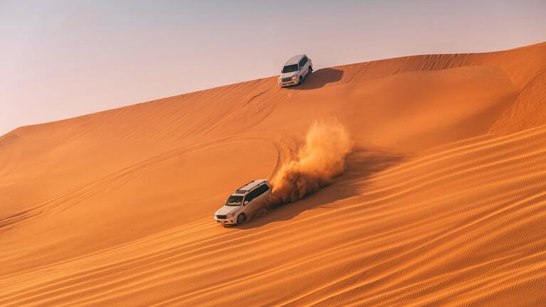 Cars driving over the dunes of the desert in Dubai
