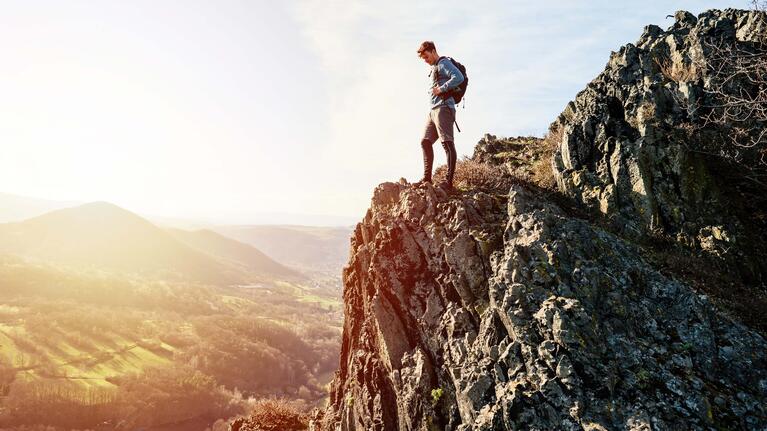 A hiker looks out from a cliffside viewpoint