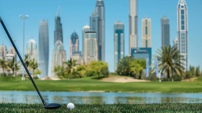 A golf ball and club with a background of the Dubai skyline