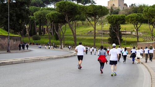 Runners jog towards a hill with Roman ruins
