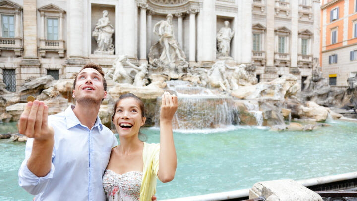 Couple making stereotypical Italian hand gestures in front of Trevi Fountain