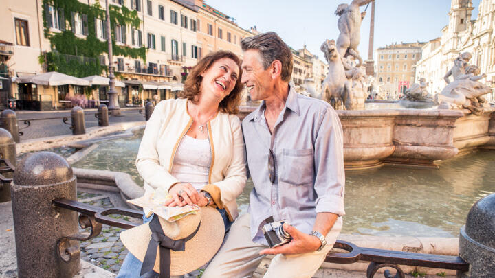 Happy senior couple sitting by fountain at Navona Square