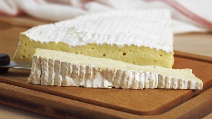 Large and small slice of Brie on wooden board