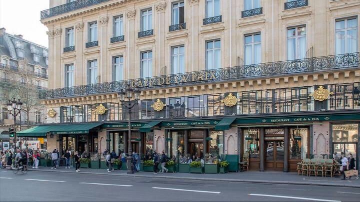 Exterior frontage of Cafe de la Paix, Paris, showing balcony, gold detail and green awnings