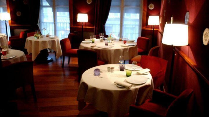 Tastefully lit interior of Marsan restaurant, with wooden floor and four set tables