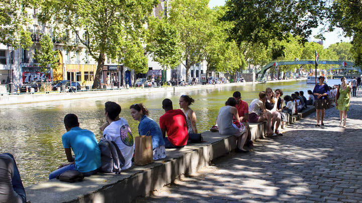 People sitting in the sunshine alongside the Canal Saint-Martin in Paris