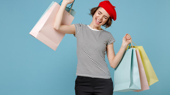 A lady in a beret and striped shirt carries several shopping bags