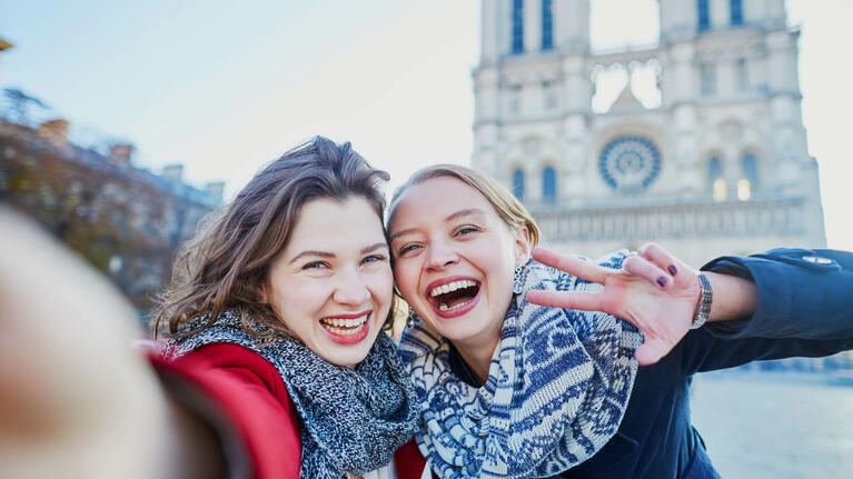 Two tourists take a selfie outside of Notre Dame Cathedral