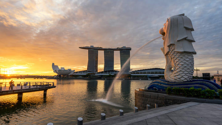 Singapore's Merlion statue at sunset with the Marina Bay Sands resort in the background.